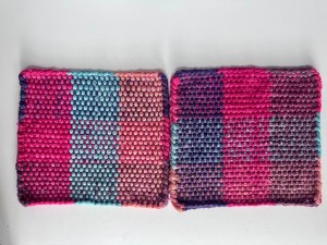Two potholders in a color combination of light blue, reds, pinks, and purples.