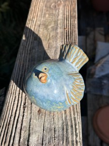 Ceramic fat bluebird with patina of gold mostly on wings and tail. Beak is slightly ajar and pointed upward as if in greeting.
