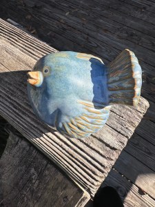 Ceramic fat bluebird with patina of gold mostly on wings and tail. Beak is slightly ajar and pointed upward as if in greeting.
