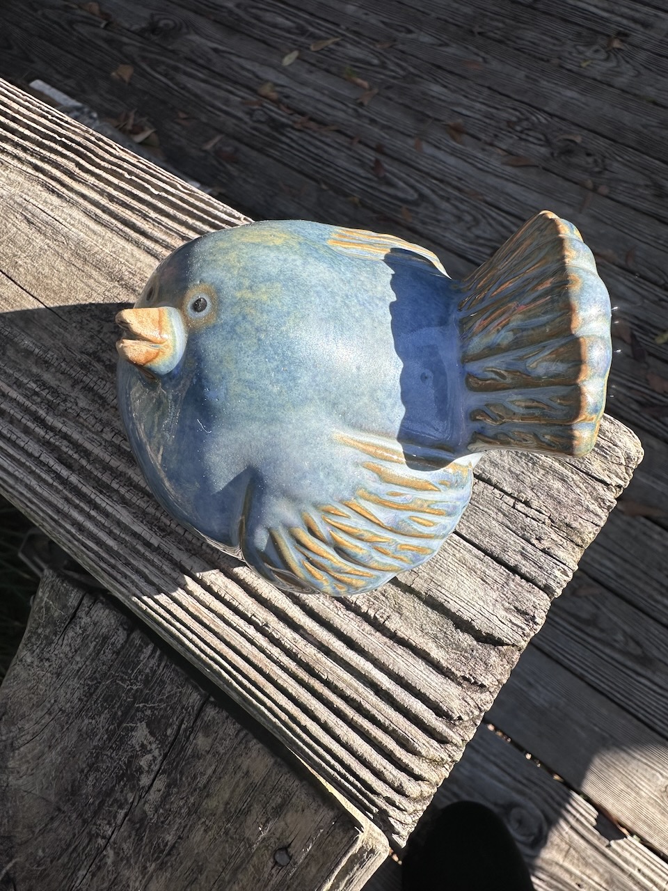 Ceramic fat bluebird with patina of gold mostly on wings and tail. Beak is slightly ajar and pointed upward as if in greeting.