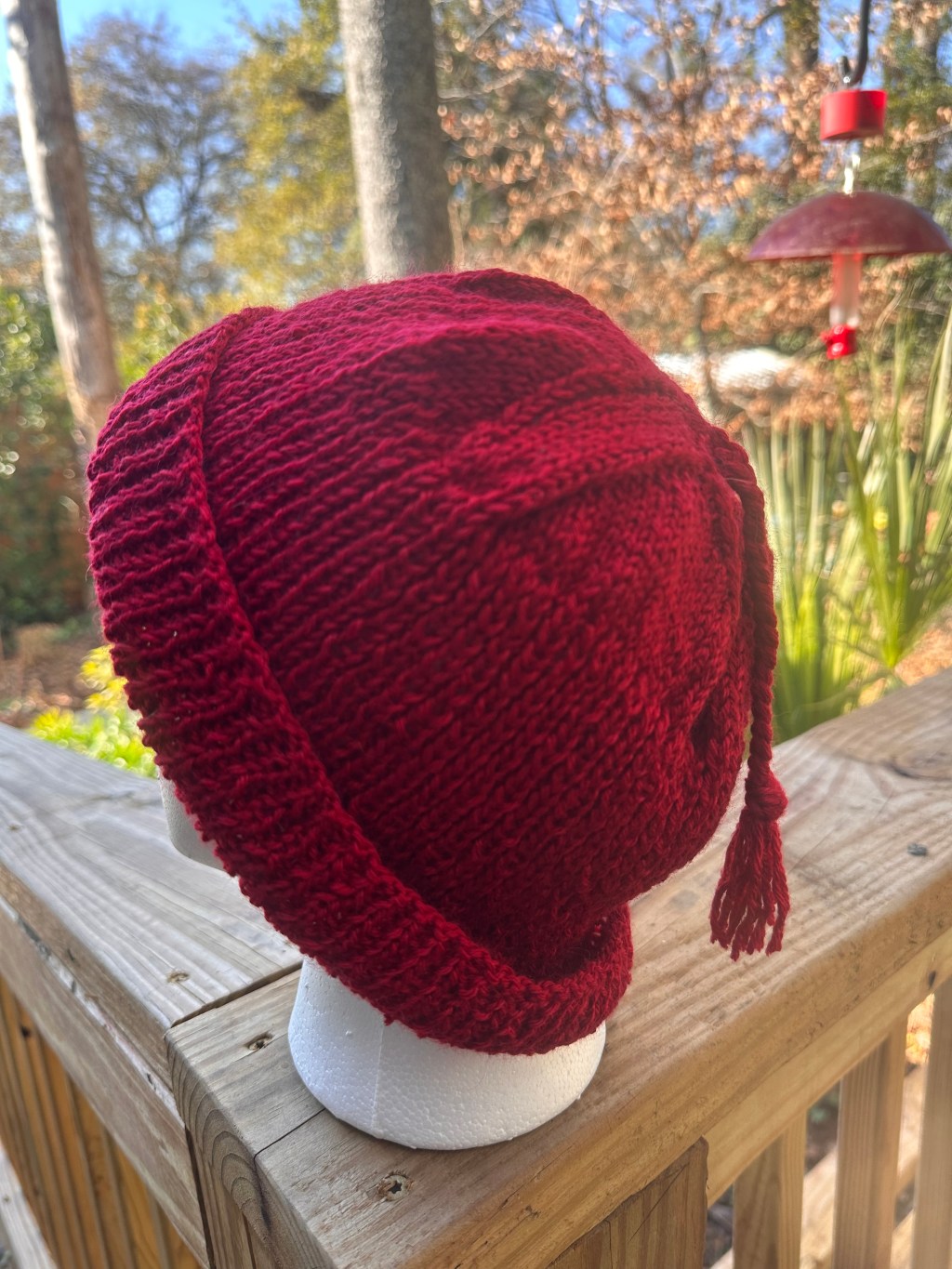 Red knitted hat with a tassel on the top.